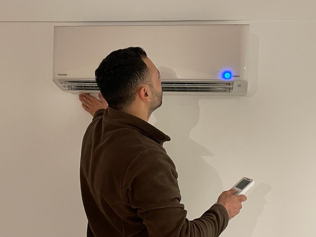 Technicien PAC Clim Paris 8 posant un climatiseur mural et une unité extérieure